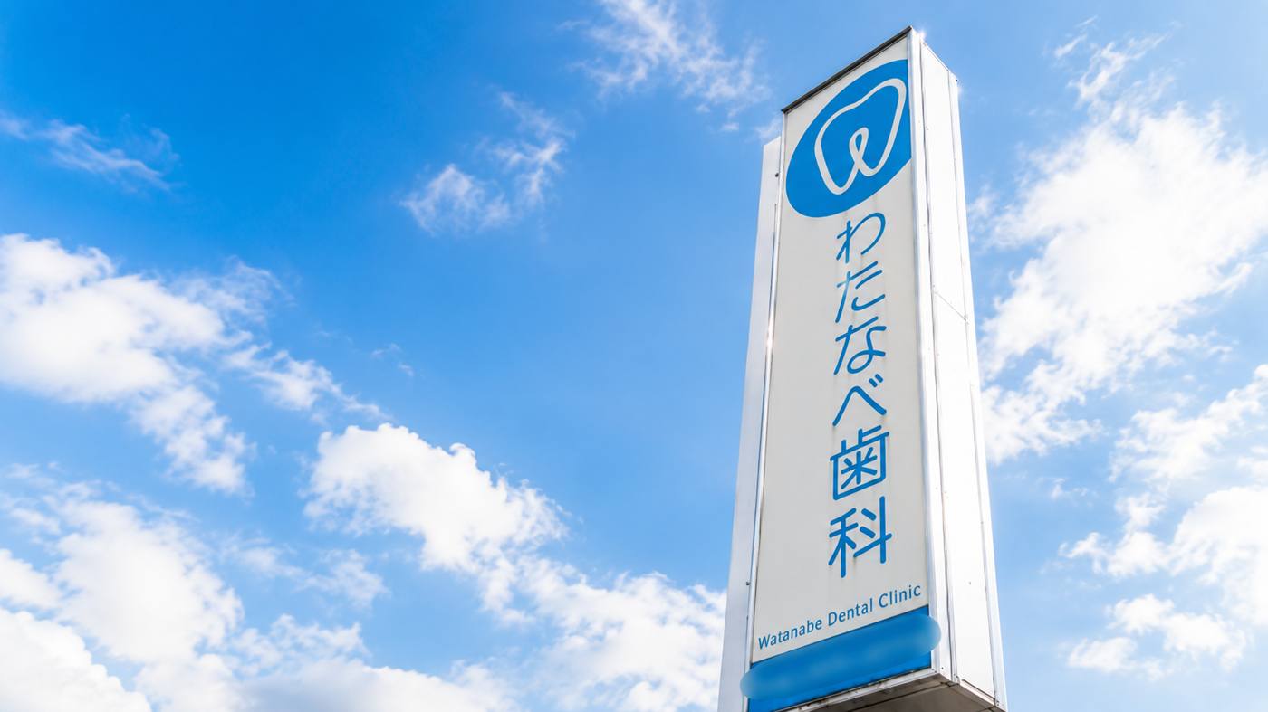 青空に映えるわたなべ歯科クリニックの看板
